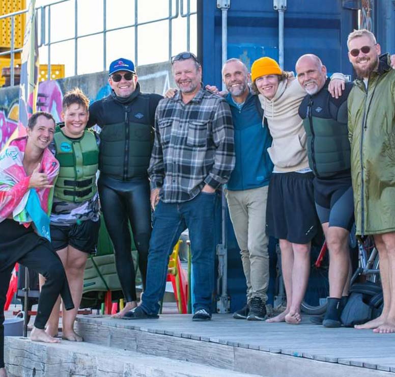 8 mænd står med armene om hinanden ved vandsportscenteret