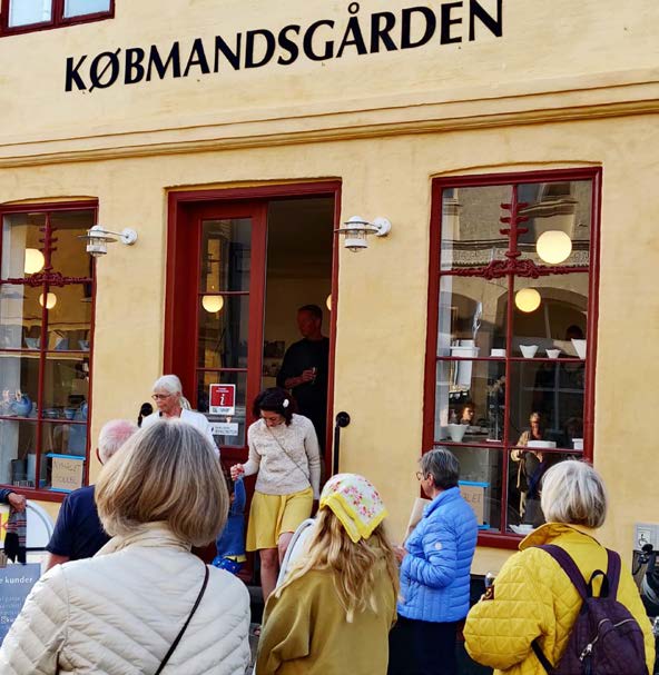 Indgangen til Købmandsgården i Skælskør - mange mennesker er på vej ind i den gule bygning
